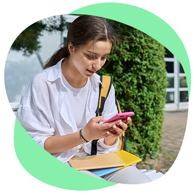 Estudiante con mochila usando su celular mientras está sentada al aire libre.