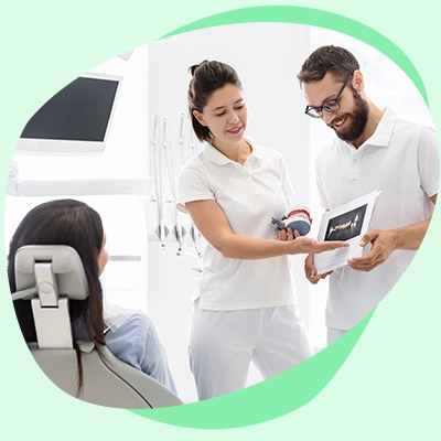 Dos dentistas en uniforme blanco enseñando radiografías dentales a un paciente en una clínica dental